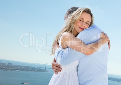 Couple hugging against sky and water