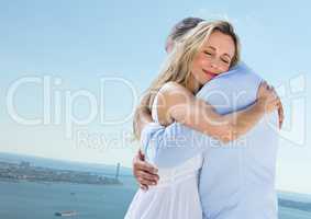 Couple hugging against sky and water