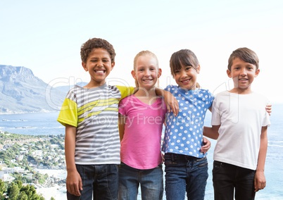 Group of kids smiling against blurry coastline