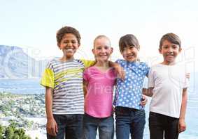 Group of kids smiling against blurry coastline