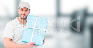 Delivery man with blue gift against blurry grey office
