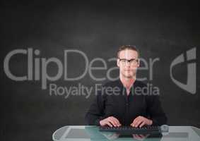 Nerd man at desk against grey wall