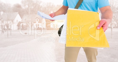 Delivery man mid section with letters against blurry housing estate