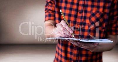 Millennial man mid section with notepad in pink room