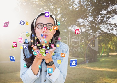 young hipster woman blowing application icons from her hands in the park