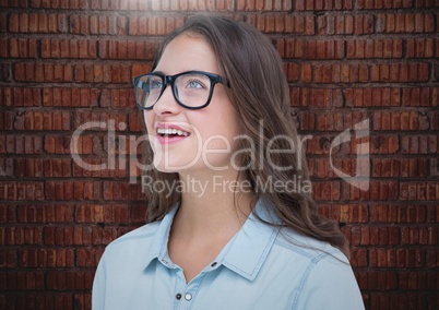 Millennials woman looking up against brick wall with flare