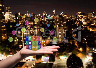 hand with applications icons cube on it. Blurred city at night