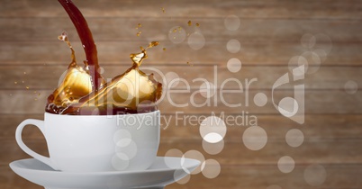 Coffee being poured into white cup with bokeh against blurry wood panel
