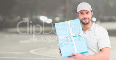 Delivery man with blue gift against blurry street