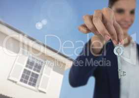 Woman Holding key in front of house and blue sky