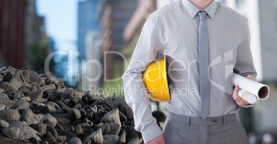 Rubble stones with Architect Construction worker holding helmet and blueprints in city