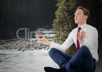 Business man meditating against river