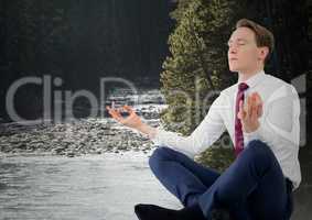 Business man meditating against river