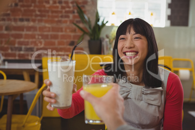 Cropped hand of man holding drink with woman in cafe