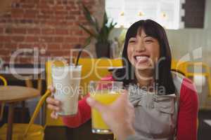 Cropped hand of man holding drink with woman in cafe