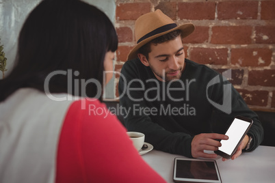 Man showing phone to girlfriend at cafe Man showing phone to girlfriend at cafe