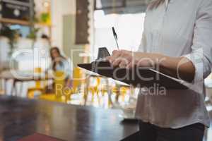 Mid section of waitress with clipboard in cafe