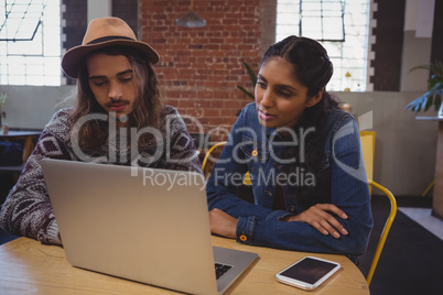 Man with friend using laptop in cafe