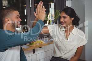 Couple giving high-five in cafe