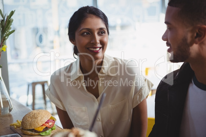 Happy young woman looking at man in cafe