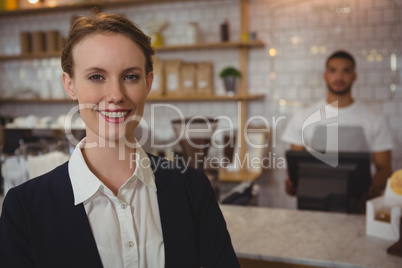 Portrait of female owner with waiter working in background