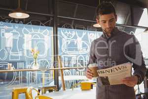 Businessman reading newspaper while having coffee
