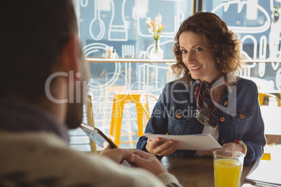 Smiling woman with document looking at man in cafe