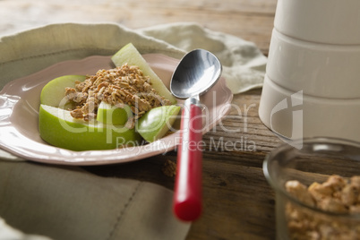 Plate of breakfast cereals with fruits on wooden table