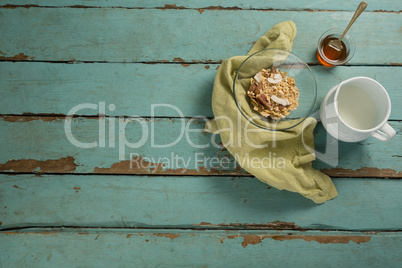 Bowl of breakfast cereal, honey and milk on wooden table