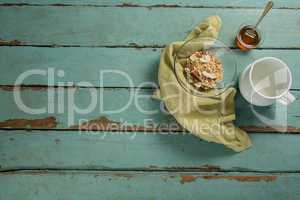 Bowl of breakfast cereal, honey and milk on wooden table