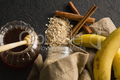Honey, banana, oatmeal, cinnamon sticks on black background