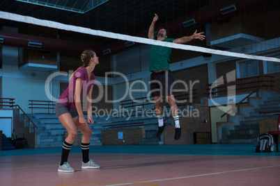 Woman looking at teammate jumping at volleyball court