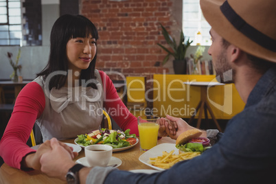 Couple with food holding hands at cafe
