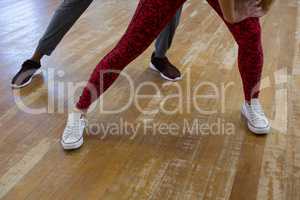 Low section of friends rehearsing dance on wooden floor