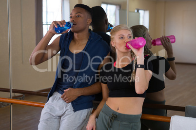 Tired dancers drinking water in studio