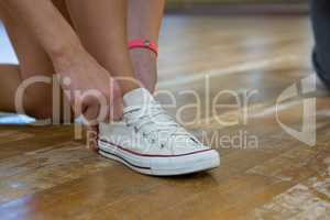 Low section of female dancer tying shoelace