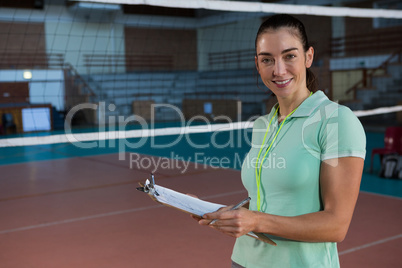 Portrait of smiling volleyball coach holding clipboard