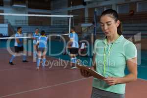 Coach holding clipboard at volleyball court