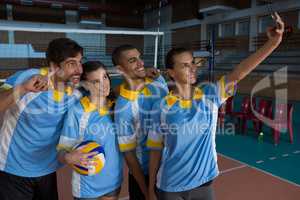 Female volleyball player with team taking selfie