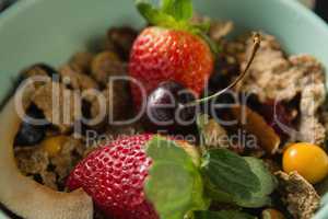 Bowl of breakfast cereals with fruits on black background