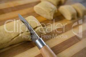 Cropped image of kitchen knife cutting dough