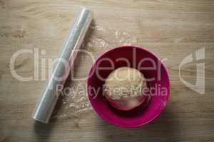 Overhead view of kneaded dough in pink bowl