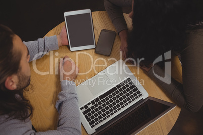 High angle view of friends with laptop and tablet in cafe