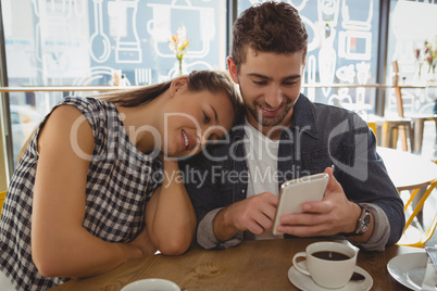 Man with woman using phone in cafe