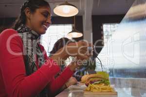 Woman photographing French fries in cafe