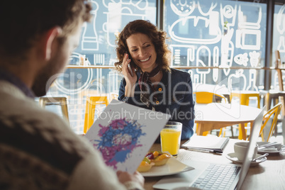 Man holding paper with painting by woman in cafe