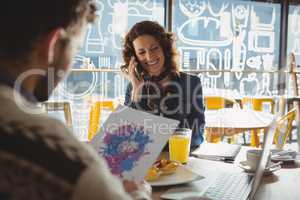 Man holding paper with painting by woman in cafe