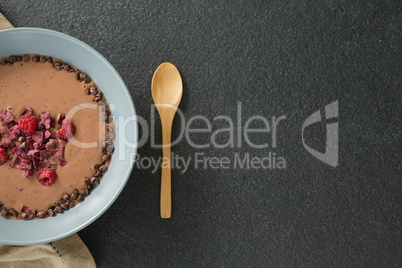 Chocolate syrup with fruits in bowl on black background