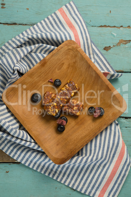 Granola bar and blueberry on wooden plate