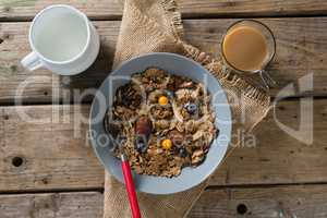 Bowl of wheat flakes, blueberry and golden berry with milk jug